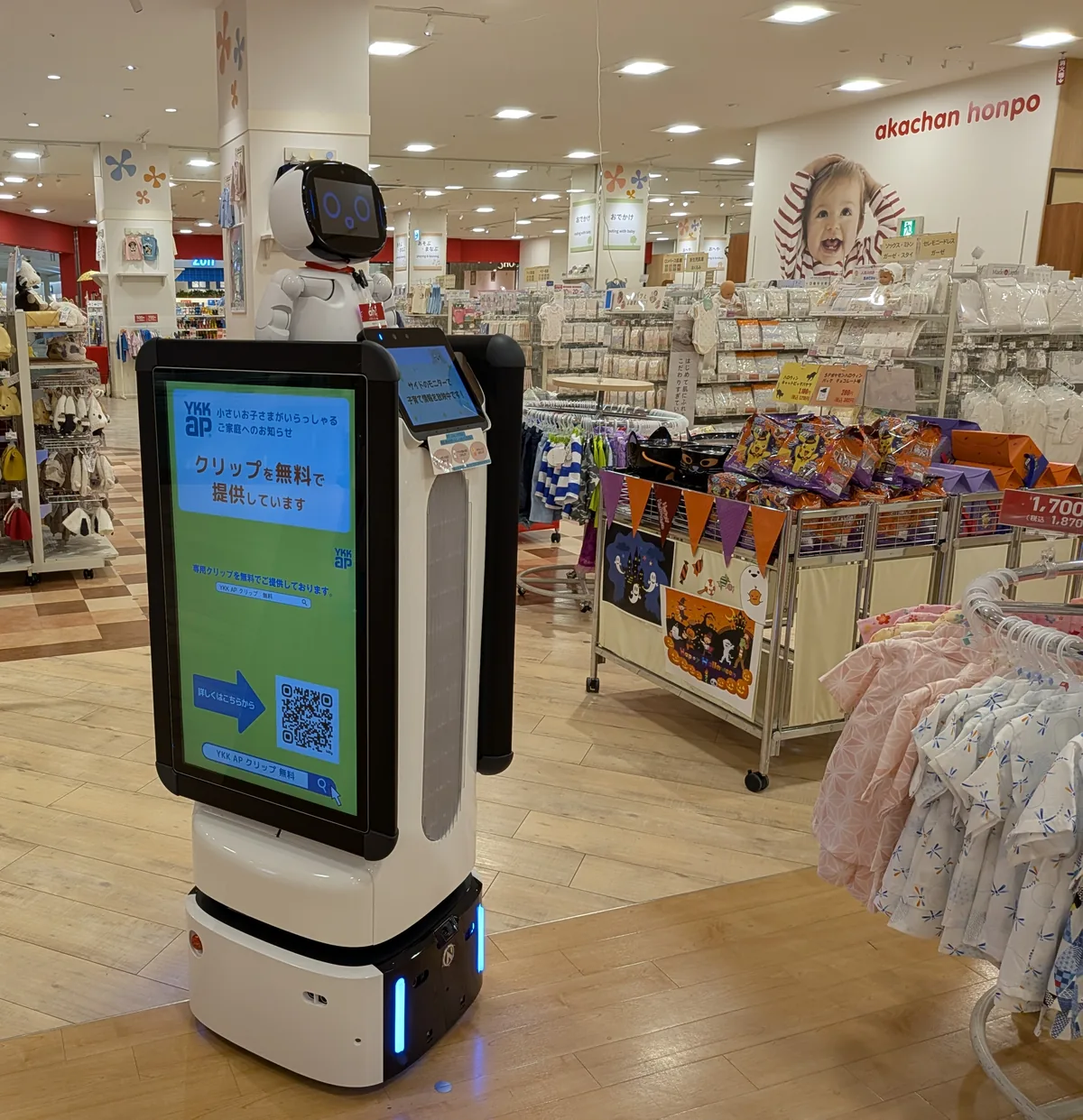 ベビー用品店の売り場で、両面ディスプレイに情報を映して立つサイネージ型 Collibot